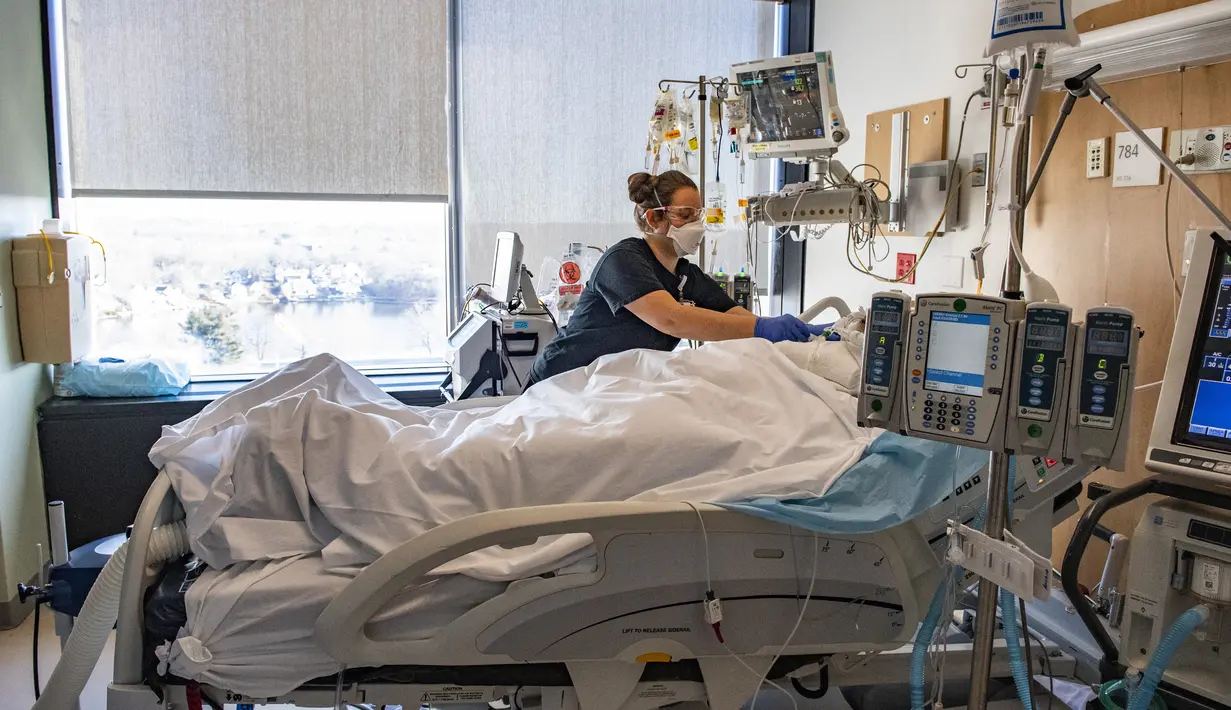 Petugas merawat pasien non-Covid-19 di dalam satu ruangan di samping kamar pasien Covid-19, di bangsal ICU UMass Memorial Medical Center di Worcester, Massachusetts, Selasa (4/1/2022). Rumah sakit mengklaim mereka dipenuhi pasien dan tidak memiliki banyak tempat tidur tersisa. (Joseph Prezioso/AFP)
