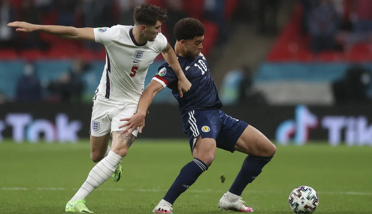 Bek Inggris, John Stones berusaha merebut bola dari penyerang Skotlandia, Che Adams pada pertandingan grup D Euro 2020 di stadion Wembley, di London, Jumat (18/6/2021). Inggris bermain imbang atas Skotlandia dengan skor 0-0. (Carl Recine/Pool Photo via AP)