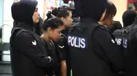 Tersangka kasus pembunuhan Kim Jong-nam, Siti Aisyah dengan kawalan polisi dibawa menuju Bandara Internasional Kuala Lumpur, Selasa (24/10). Siti terlihat mengenakan rompi anti-peluru saat mengunjungi tempat kejadian perkara itu. (AP/Sadiq Asyraf)