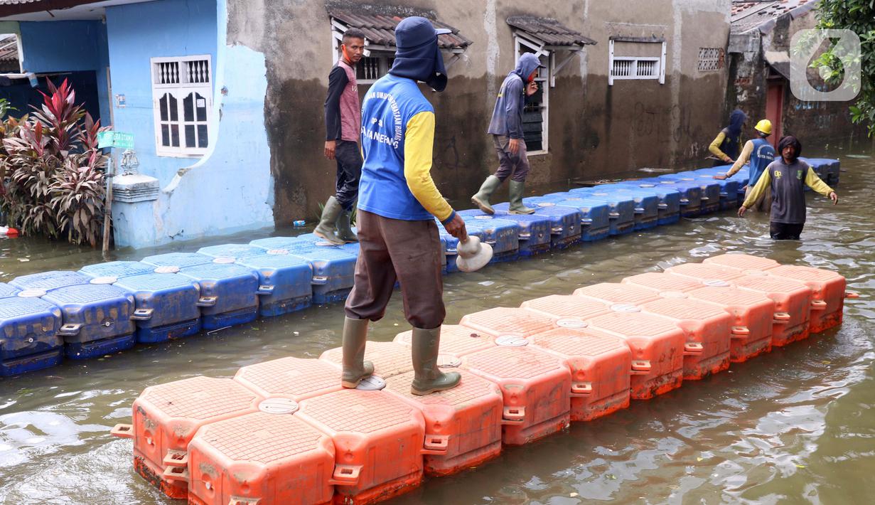 Petugas membuat jembatan apung saat banjir melanda Perumahan Periuk Damai, Tangerang, Banten, Selasa (23/2/2021). Adanya jembatan apung mempermudah warga saat melintasi banjir setinggi 2,5 meter di tempat tersebut. (Liputan6.com/Angga Yuniar)