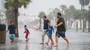 Orang-orang berjalan di sepanjang Ocean Boulevard di tengah hujan di Pantai Myrtle, Carolina Selatan (3/8/2020). Badai Isaias terus bergerak ke utara di sepanjang pesisir timur AS. (Sean Rayford/Getty Images/AFP)