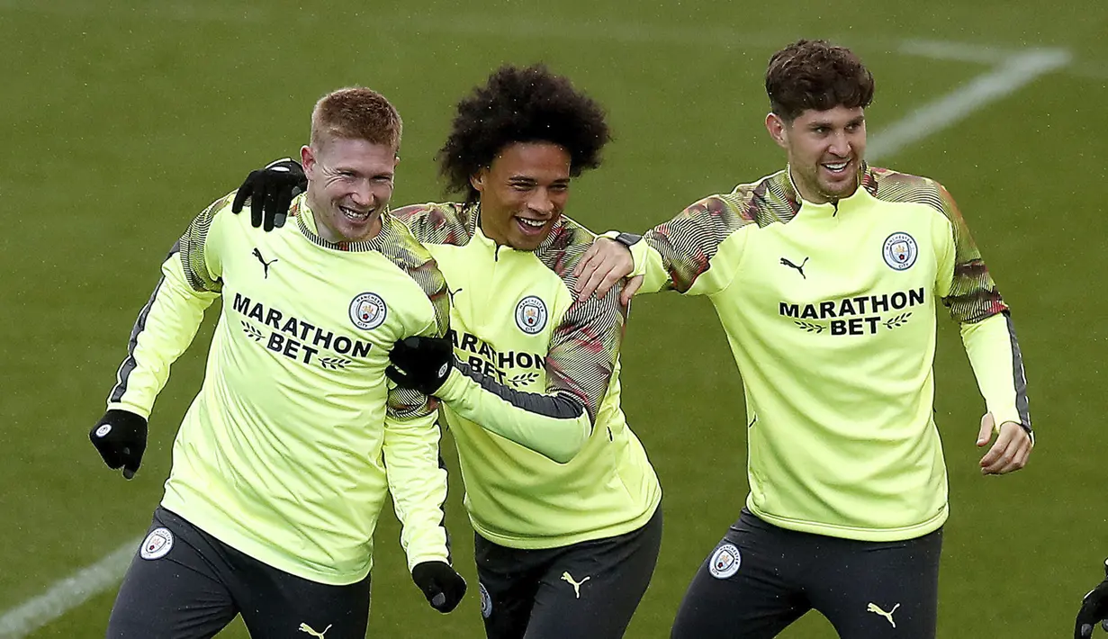 Pemain Manchester City, Kevin De Bruyne (kiri), Leroy Sane (tengah) dan John Stones bercanda selama sesi latihan tim di City Football Academy, Manchester, Inggris (25/2/2020). City akan bertanding melawan Real Madrid pada leg pertama babak 16 Liga Champions di Bernabeu. (Martin Rickett/PA via AP)