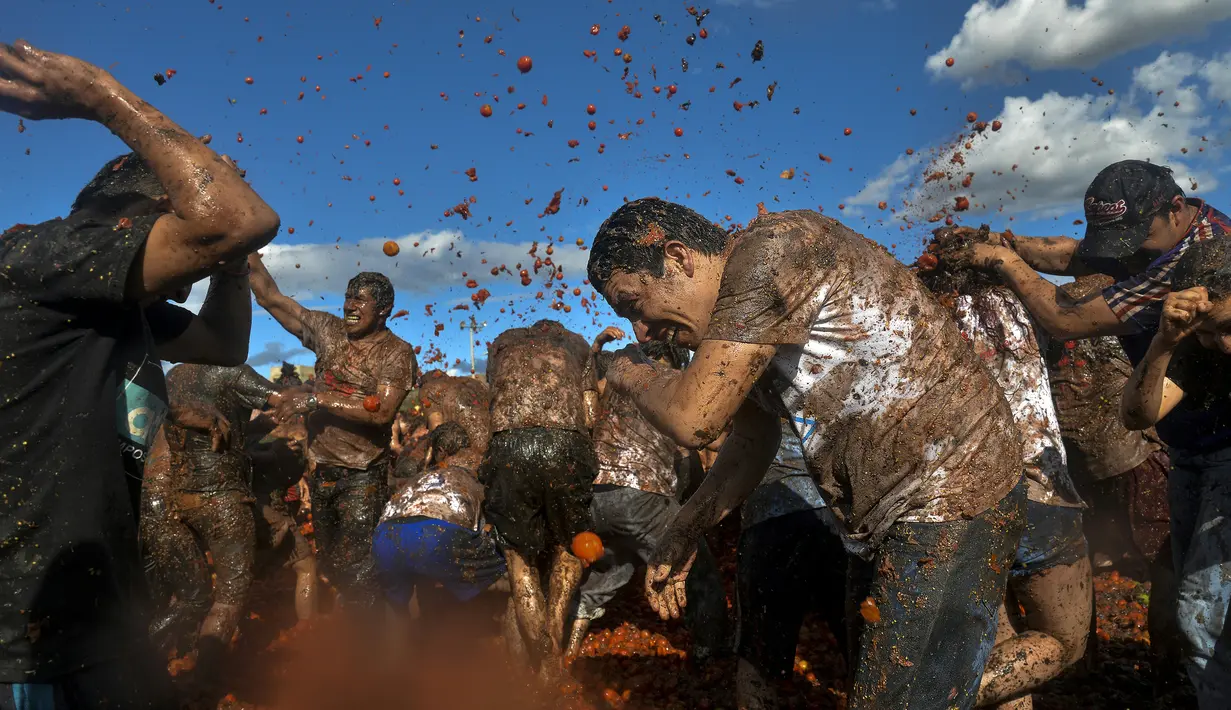 Peserta saling lempar saat perang tomat dalam Festival Tomatina di Sutamarchan, Boyaca, Kolombia, Minggu (2/6/2019). Perang tomat digelar dengan tujuan menarik wisatawan untuk berkunjung ke Kolombia. (Diana SANCHEZ/AFP)