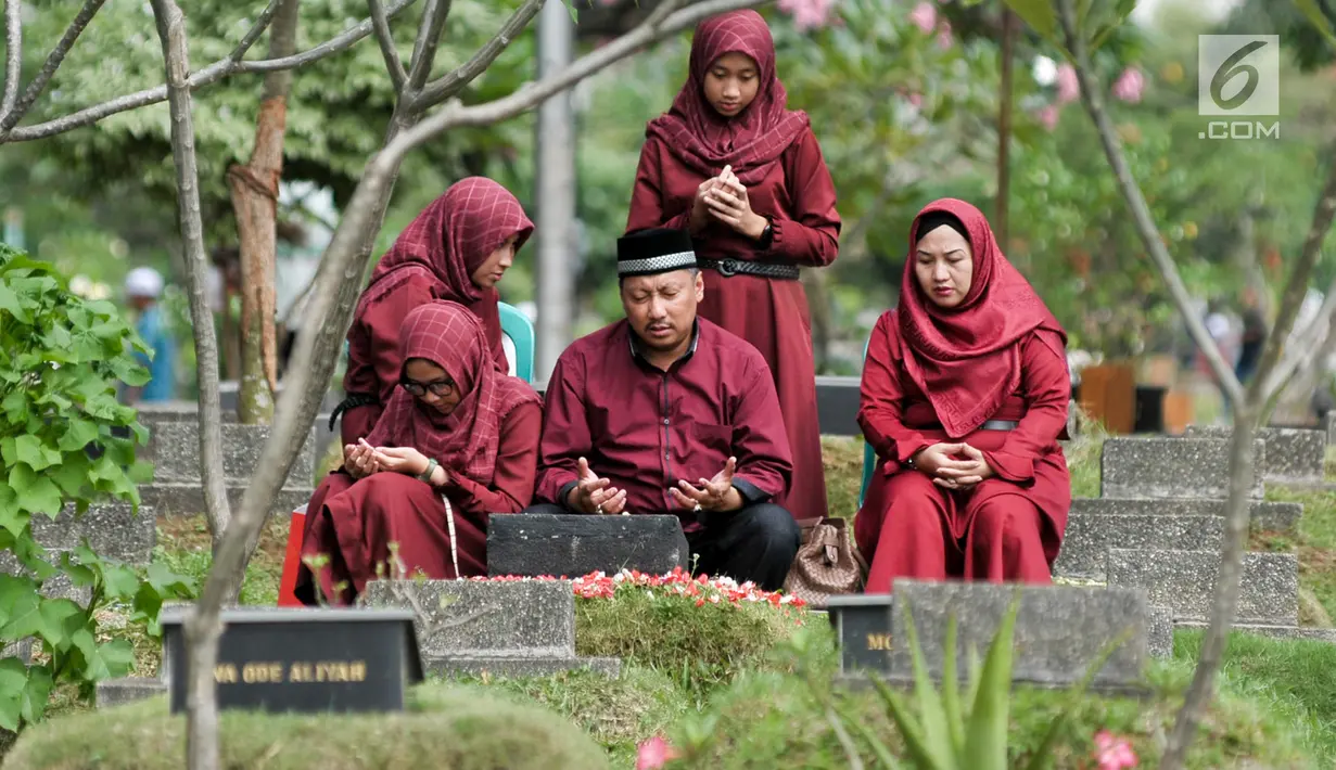 Umat Muslim berdoa saat ziarah kubur di Tempat Pemakaman Umum (TPU) Karet Bivak, Jakarta, Minggu (25/6). Hari pertama Lebaran, sejumlah warga memadati TPU untuk melangsungkan tradisi ziarah usai salat Idul Fitri. (Liputan6.com/Yoppy Renato)