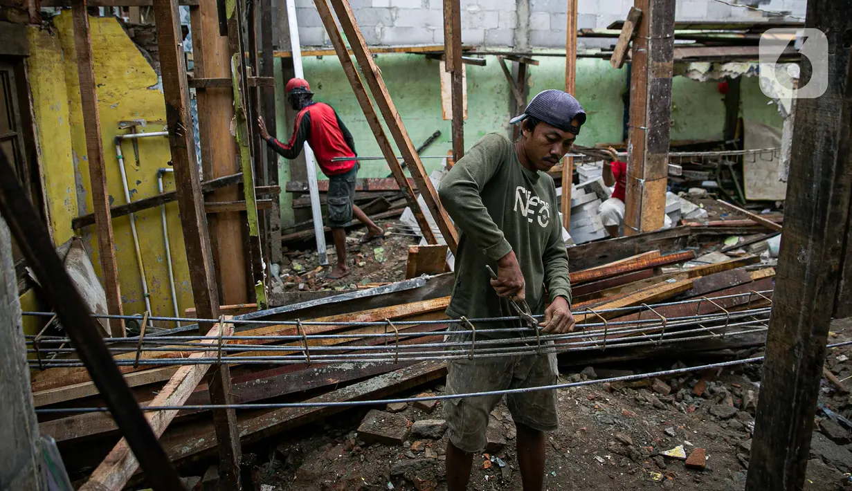Pekerja menyelesaikan pembangunan rumah panggung di dekat bantaran Kali Ciliwung, Kampung Melayu, Jakarta, Rabu (7/4/2021). Pemerintah Provinsi DKI Jakarta melakukan renovasi terhadap 40 hunian warga Kampung Melayu menjadi rumah panggung. (Liputan6.com/Faizal Fanani)