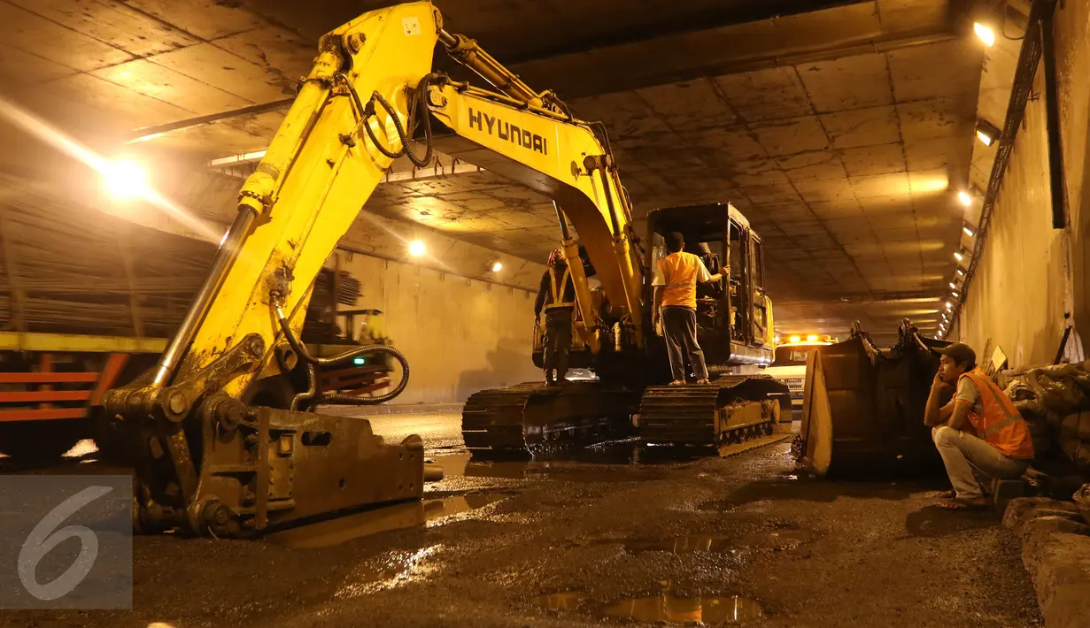 Pekerja menggunakan alat berat untuk memperbaiki jalan yang rusak berlubang di ruas Tol JORR tepatnya di terowongan Pasar Rebo, Jakarta, Senin (29/2) malam. Kondisi jalan yang rusak itu menyebabkan kemacetan panjang. (Liputan6.com/Herman Zakharia)