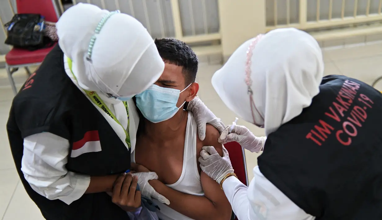 Reaksi seorang siswa SMA saat menerima dosis vaksin virus corona COVID-19 Pfizer di Rumah Sakit Zainoel Abidin, Banda Aceh, Aceh, Selasa (9/11/2021). Vaksinasi COVID-19 di kalangan warga Kota Banda Aceh tembus 80 persen. (CHAIDEER MAHYUDDIN/AFP)