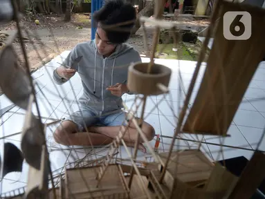 Perajin menyelesaikan pembuatan miniatur kapal pinisi yang terbuat dari limbah bambu di Pondok Benda, Pamulang, Tangerang Selatan, Senin (09/11/2020). Kerajinan berbahan bambu bekas yang dijual dengan harga berkisar Rp.50 ribu hingga Rp.250 ribu tergantung ukurannya. (merdeka.com/Dwi Narwoko)
