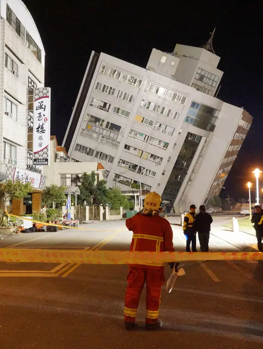 Petugas penyelamat memblokir area di dekat bangunan yang miring karena pondasinya ambruk usai terjadi gempa di Hualien, Taiwan (7/2). (AFP Photo/Paul Yang)