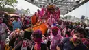 Umat Hindu berkerumun di sekitar mobil Rolls Royce 1921 yang dimodifikasi membawa patung dewa Krishna melalui bangunan bersejarah Howrah Bridge selama festival Holi di Kolkata, India, Minggu, 5 Maret 2023. (AP Photo/Bikas Das)