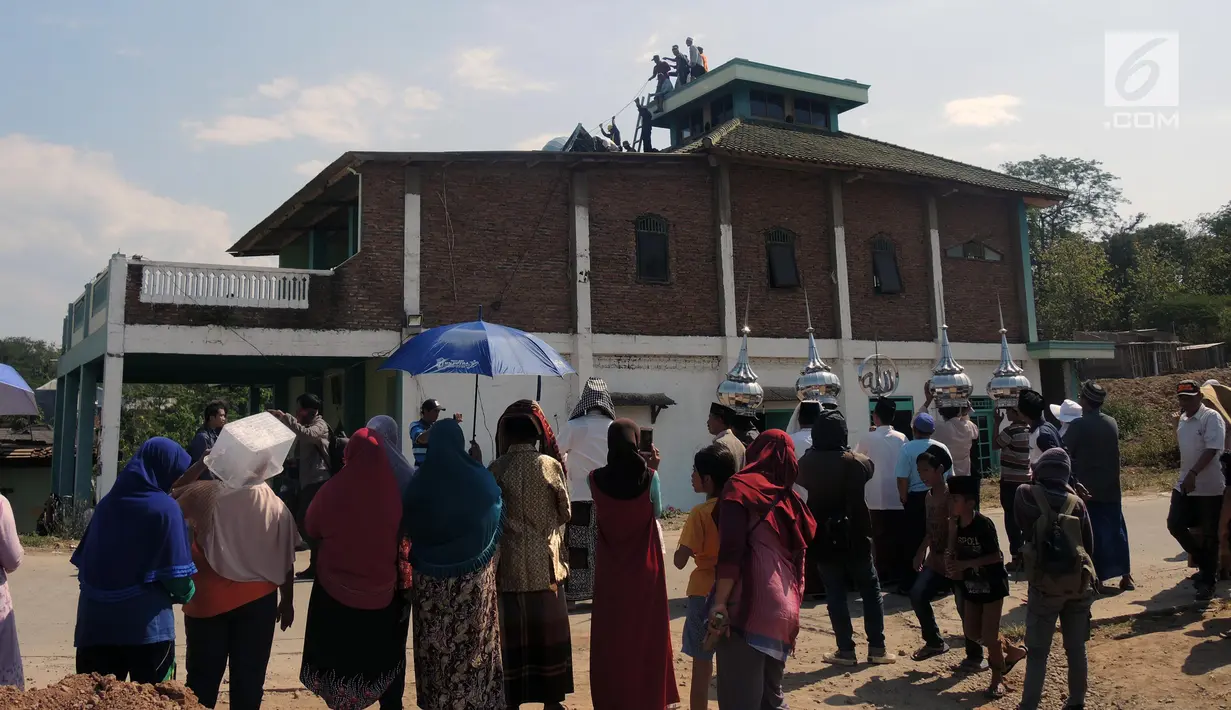 Warga menyaksikan penurunan kubah Masjid Baitul Mustaghfirin yang berada di tengah tol fungsional Batang-Semarang, Jumat (28/9). Pembongkaran masjid secara fisik diperkirakan butuh waktu 2 hari. (Liputan6.com/Gholib)