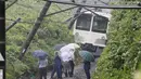 Petugas mengamati kereta yang tergelincir dalam tanah longsor yang disebabkan topan mindulle di Higashimurayama, Tokyo, Senin (22/8). Ratusan penerbangan serta perjalanan kereta api di Tokyo dibatalkan akibat terjangan Topan Mindulle. (Jiji Press/AFP)