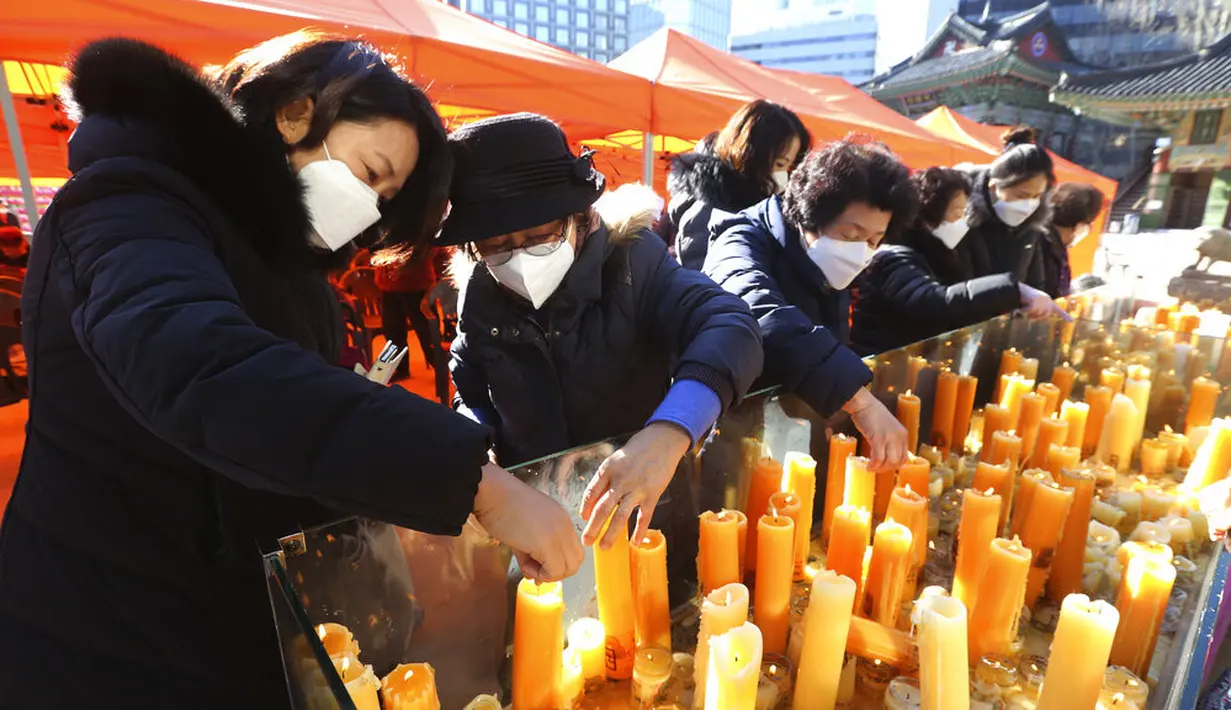 Para orangtua meletakkan lilin selama kebaktian khusus untuk mendoakan keberhasilan anak-anak mereka dalam ujian masuk perguruan tinggi di Kuil Buddha Jogyesa, Seoul, Korea Selatan, Kamis (3/12/2020). Ujian diikuti ratusan ribu siswa, termasuk puluhan siswa pasien COVID-19. (AP Photo/Ahn Young-joon)
