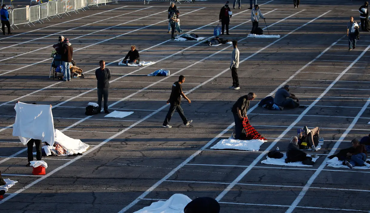 Orang-orang bersiap tidur di tempat-tempat yang ditandai dengan kotak-kotak yang diberi jarak untuk social distancing di lahan parkir di Las Vegas, Senin (30/3/2020). Tempat parkir itu diubah menjadi tempat penampungan sementara untuk para tunawisma di ttengah pandemi Covid-19. (AP/John Locher)