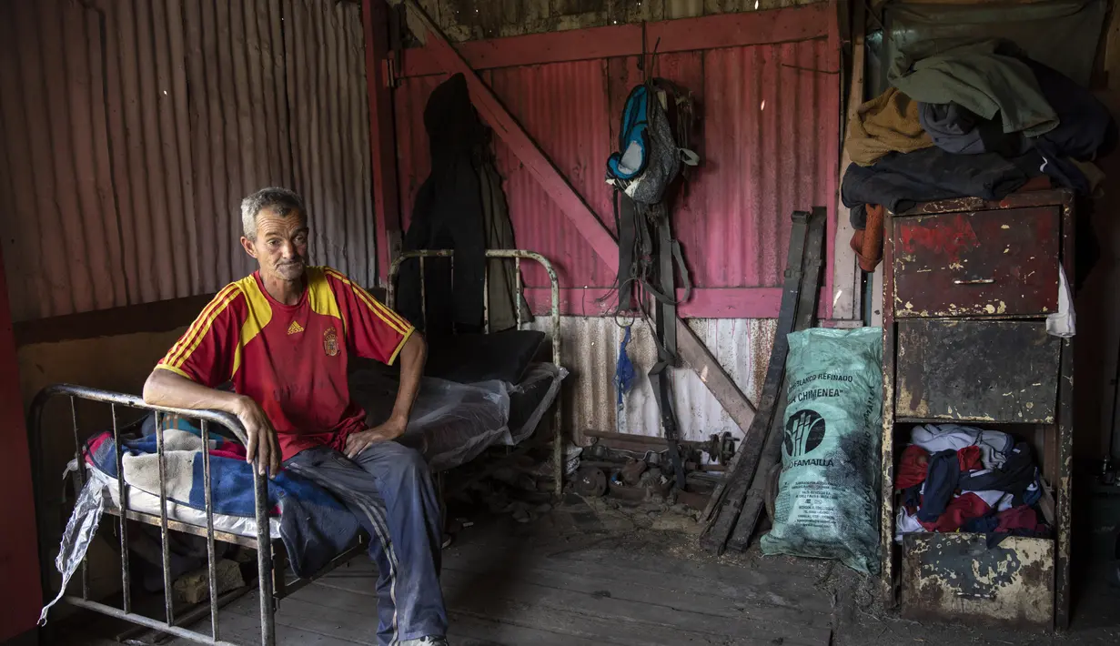 Juan Pablo Ibarra, 51, menonton televisi di kamarnya setelah mendaur ulang barang di pagi hari, di tempat pengumpulan daur ulang di pinggiran kota Buenos Aires, Argentina (14/12/2021). Pemilik tempat pengumpulan mengizinkan Ibarra untuk tinggal di sana. (AP Photo/Rodrigo Abd)