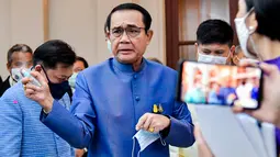 PM Thailand, Prayut Chan-O-Cha menyemprotkan pembersih tangan ke wartawan untuk menghindari pertanyaan perombakan kabinet selama konferensi pers di Bangkok, Selasa (9/3/2021). Sebelum menyemprot, Prayuth mengatakan kepada wartawan untuk mengurus urusan mereka sendiri. (HO/ROYAL THAI GOVERNMENT/AFP)