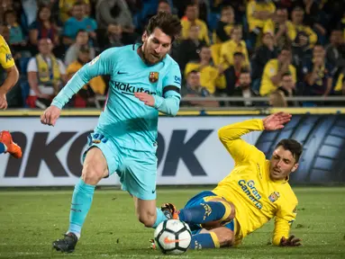 Pemain Barcelona Lionel Messi berebut bola dengan bek Las Palmas, Ximo Navarro Jimenez pada jornada ke-26 La Liga 2017-2018 di Estadio Gran Canaria, Kamis (1/3). Barcelona gagal menang karena tuan rumah menahan imbang dengan skor 1-1. (DESIREE MARTIN/AFP)