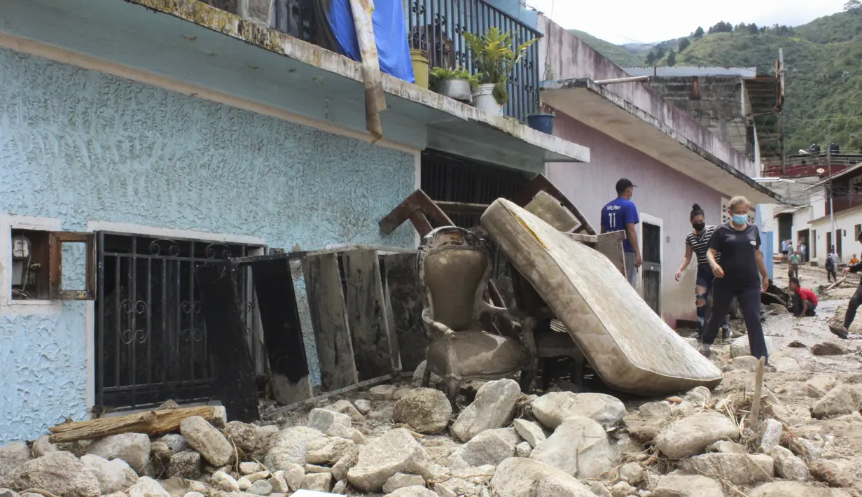 Puing-puing dari dalam rumah berserakan di jalan setelah banjir dan tanah longsor yang dipicu hujan lebat di Tovar, negara bagian Merida, Venezuela, Kamis (26/8/2021). Gubernur Merida, Ramon Guevara, mengatakan lebih dari 1.200 rumah hancur dan 17 orang masih dalam pencarian. (AP Photo/Luis Bustos)