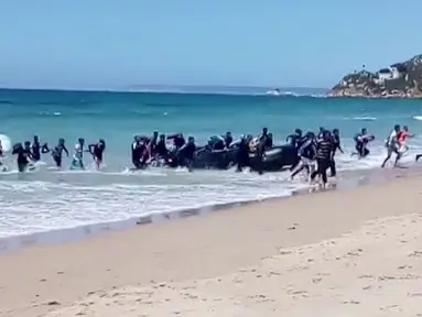 Puluhan imigran datang menggunakan perahu karet dan menyerbu pantai Cadiz di Spanyol selatan, 9 Agustus 2017. Para turis yang tengah menikmati suasana pantai dan sinar matahari di Spanyol itu mendadak terkejut. (Carlos Sanz via AP)