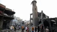 Orang-orang berdiri di antara puing-puing masjid yang hancur selama serangan udara Israel, di Kota Gaza pada 9 Oktober 2023. (Mahmud HAMS/AFP)