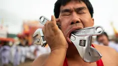 Penganut kuil Loem Hu Thai Su menusukkan kunci inggris ke pipinya saat festival vegetarian tahunan di Phuket, Thailand, Jumat (12/10). Acara ini dikenal juga dengan 'Nine Emperor Gods' atau hari 'Sembilan Kaisar Dewa'. (Jewel Samad/AFP)