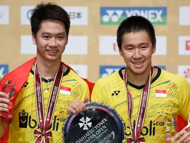 Pasangan ganda putra Indonesia, Kevin Sanjaja Sukamuljo (kiri) dan Marcus Feraidi Gideon berpose dengan trofi juara Japan Open 2017 di Tokyo, Jepang, (24/9). Kevin/Marcus  mengalahkan wakil tuan rumah, Takuto Inoue/Yuki Kaneko. (AFP Photo/Toru Yamanaka)