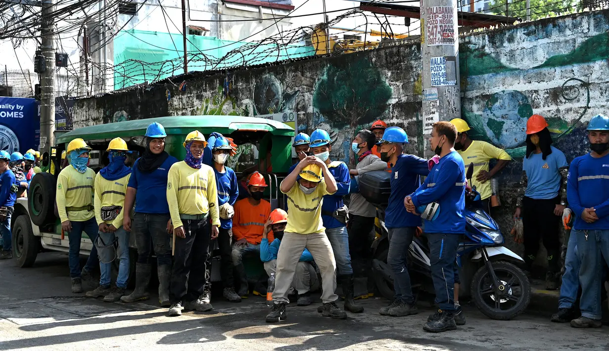 Pekerja konstruksi menyelamatkan diri dengan keluar bangunan setelah gempa berkekuatan magnitudo 7,1 terasa di Manila, Filipina, Rabu (27/7/2022). Titik gempa berada 11 Km Dolores, Filipina, dengan kedalaman dilaporkan 10 Km. (JAM STA ROSA/AFP)