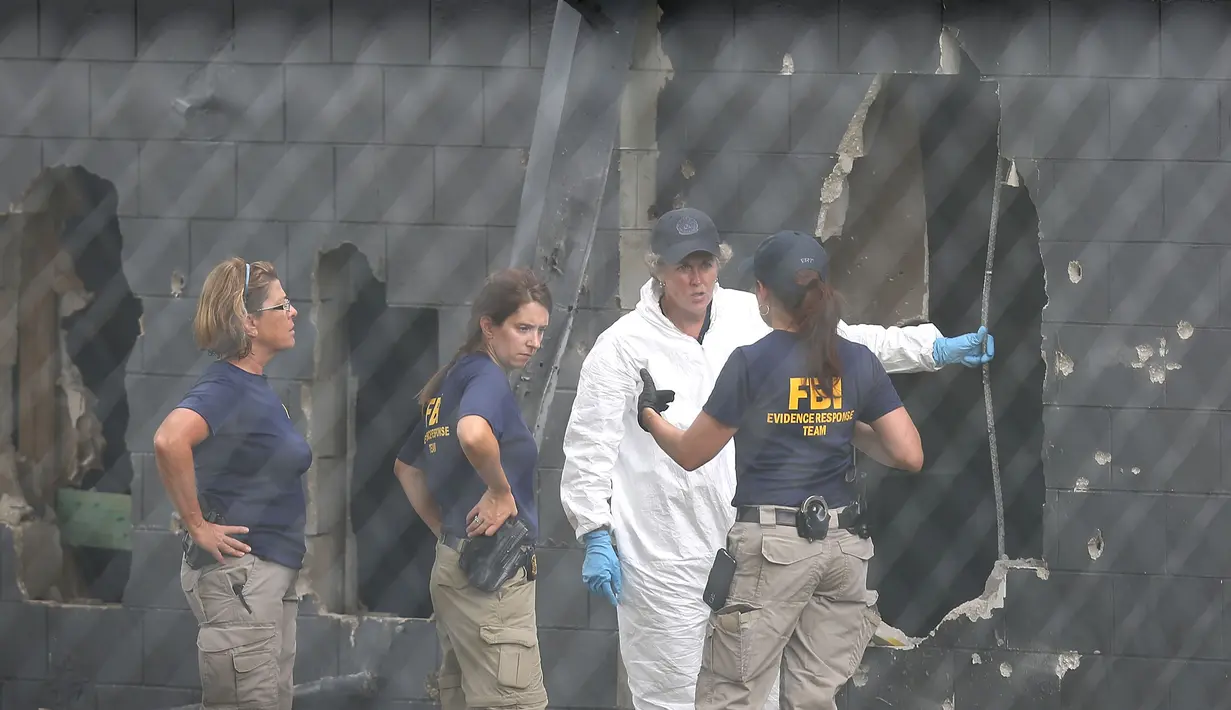Petugas FBI menyelidiki dinding belakang klub malam gay Pulse di Kota Orlando, Florida, AS, Minggu (12/6). Penembakan brutal yang dilakukan Omar Mateen di klub tersebut menewaskan 50 orang dan melukai 53 lainnya. (Joe Raedle/Getty Images/AFP)