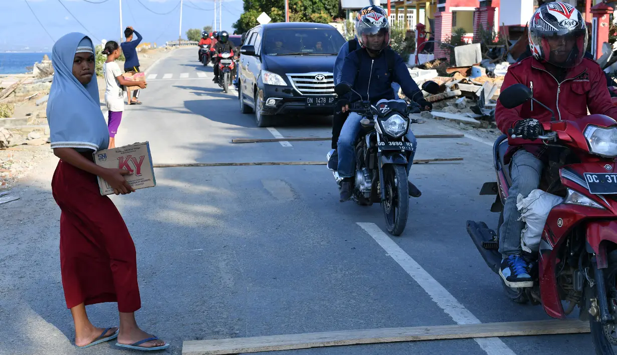 Anak-anak yang terkena dampak gempa meminta sumbangan pada pengguna jalan yang melintas di desa Loli Pesua, Donggala, Selasa (2/10). Akibat terlambatnya pasokan bantuan, mereka terpaksa meminta sumbangan hingga turun ke jalan. (AFP PHOTO / ADEK BERRY)