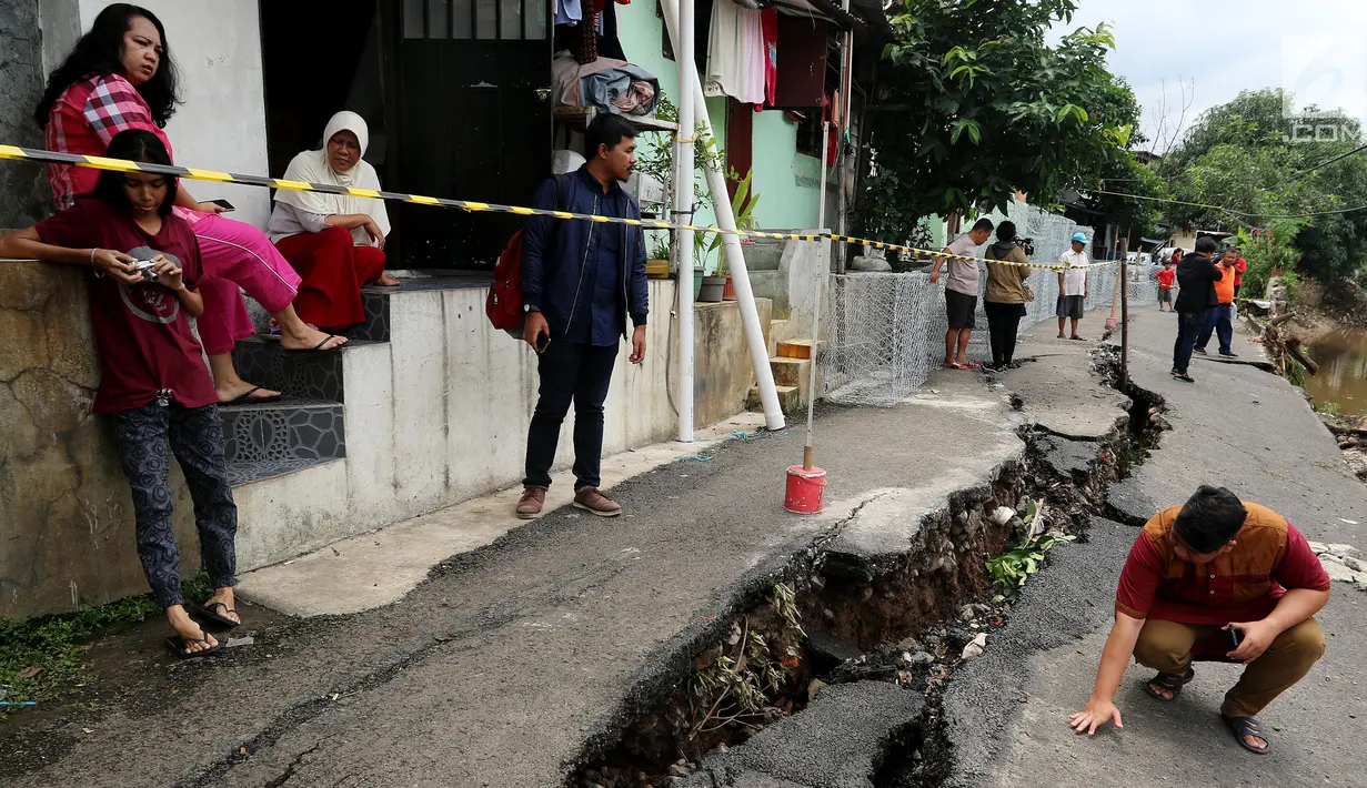 Warga melintas di tepian jalan yang di beri garis pembatas karena retak di Kelurahan Kebon Manggis, Kecamatan Matraman, Jakarta Timur, Jumat (16/2). Sementara untuk penyebabnya sendiri belum diketahui secara pasti. (Liputan6.com/Johan Tallo)