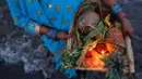 Seorang wanita membawa sesaji saat ritual Chhat Puja di Mumbai, India (7/11). Dalam ritual menyembah Dewa Matahari ini mereka meminta kesejahteraan, dan kemakmuran. (Reuters/Danish Siddiqui)