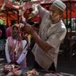 Pedagang memotong daging sapi dagangannya pada perayaan tradisi Meugang Ramadan 1440 Hijriah di Banda Aceh, 4 Mei 2019. Meugang merupakan tradisi turun temurun masyarakat Aceh dengan membeli, mengolah, hingga menyantap daging bersama keluarga. (CHAIDEER MAHYUDDIN/AFP)