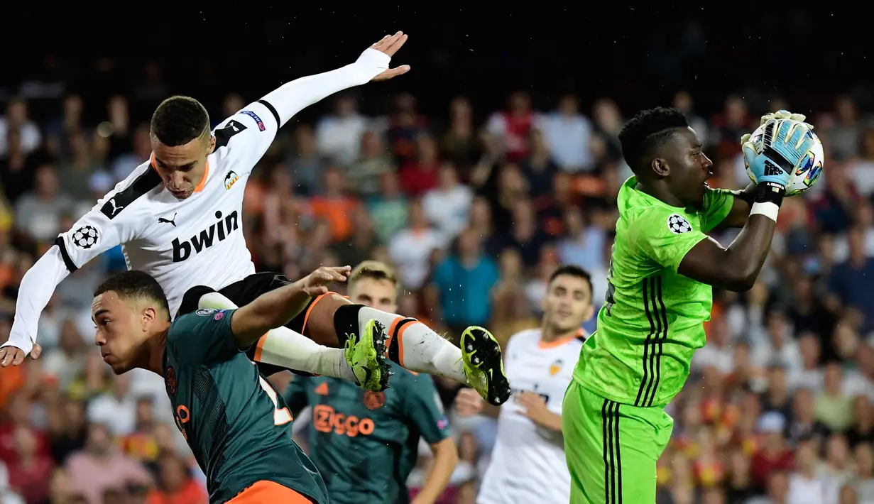 Kiper Ajax Amsterdam, Andre Onana menghalau bola yang mengarah ke pemain Valencia, Rodrigo Moreno (tengah pada laga lanjutan Grup H Liga Champions 2019/2020 di Mestalla Stadium, Valencia, 2 Oktober 2019. (AFP/Javier Soriano)