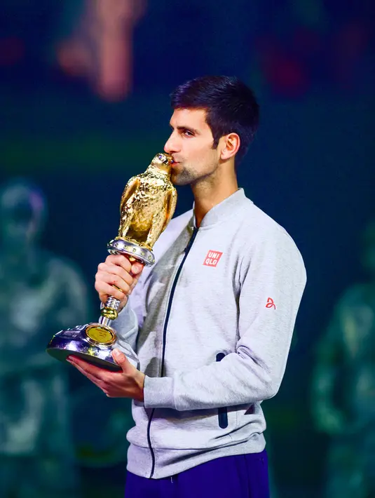 Petenis Serbia, Novak Djokovic mencium trofi Qatar Open 2017 usai menaklukkan petenis Skotlandia, Andy Murray dalam final turnamen Qatar Terbuka di Doha, Sabtu (7/1). Djokovic berhasil mempertahankan gelar Qatar Terbuka.  (AP Photo/Alexandra Panagiotidou)