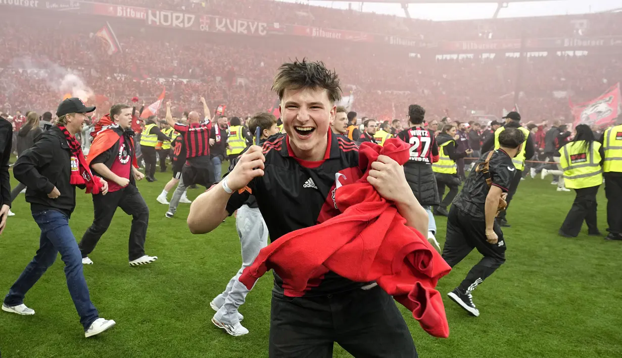 Ekspresi bahagia seorang suporter Bayer Leverkusen merayakan keberhasilan timnya memastikan gelar juara Liga Jerman 2023/2024 setelah mengalahkan Werder Bremen di BayArena, Leverkusen, Jerman, Senin (15/04/2024) WIB. (AP Photo/Martin Meissner)