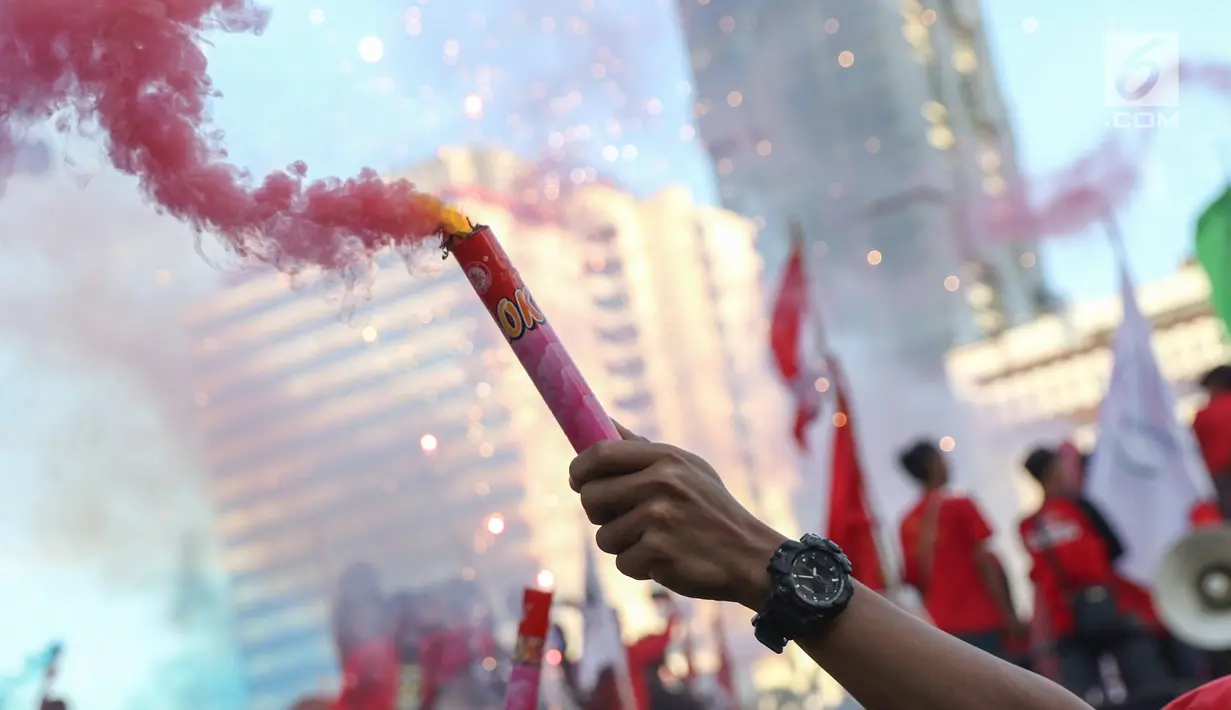 Sejumlah buruh menyalakan bom asap saat menutup aksi Hari Buruh Internasional di Jalan Medan Merdeka Barat, Jakarta, Rabu (5/1/2019). Aksi May Day 2019 di Jakarta ditutup oleh buruh dengan menyalakan kembang api sebagai simbol berjalannya demo dengan damai. (Liputan6.com/Helmi Fithriansyah)
