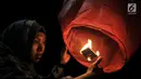 Pengunjung menyalakan api sebelum menerbangkan lampion saat perayaan Tahun Baru Imlek di Pantai Lagoon, Ancol, Jakarta, Selasa (5/2) malam. Sebanyak 500 lampion dilepas dalam  rangka menutup Festival Imlek di Ancol. (Merdeka.com/Iqbal S Nugroho)