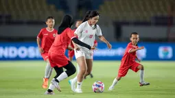 Pemain Timnas putri Indonesia, Safira Ika (tengah) menguasai bola pada laga eksibisi antara 6 pemain Timnas Putri Indonesia menghadapi 30 pemain SSB Putri Surakarta FC U-12 dalam rangkaian acara penutupan Piala Presiden 2024 di Stadion Manahan, Solo, Minggu (4/8/2024). (Bola.com/Bagaskara Lazuardi)