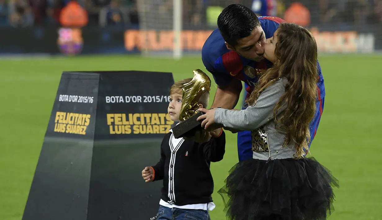 Striker Barcelona, Luis Suarez, mencium putrinya saat menunjukan Sepatu Emas jelang laga La Liga melawan Granada di Stadion Nou Camp, Spanyol, Sabtu (29/10/2016). Suarez meraih gelar ini usai mencetak 40 gol pada musim lalu. (AFP/Lluis Gene)