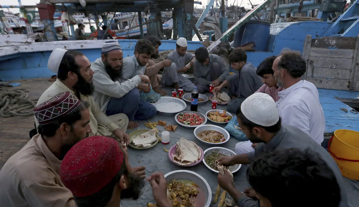 Nelayan berbuka puasa selama bulan suci Ramadhan, di galangan kapal, di Karachi, Pakistan, Selasa (20/4/2021). (AP Photo / Fareed Khan)