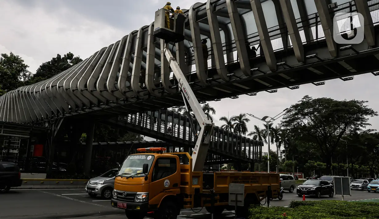 Pasukan kuning dari Dinas Bina Marga DKI Jakarta melakukan perawatan Jembatan Penyeberangan Orang (JPO) di Kawasan Sudirman, Senin (29/3/2021). Kegiatan tersebut dilakukan agar bersih terhidar dari debu serta para pemakai jembatan itu merasa aman dan nyaman. (Liputan6.com/Johan Tallo)