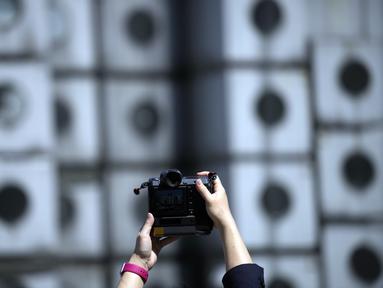 Seorang pria mengambil foto lokasi pembongkaran Nakagin Capsule Tower, bangunan ikonik yang dirancang arsitek Jepang Kisho Kurokawa pada tahun 1972, di distrik Ginza Tokyo, Selasa (12/4/2022). Pekerjaan pembongkaran menara 140 unit kapsul tersebut dimulai Selasa. (AP Photo/Eugene Hoshiko)