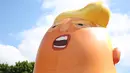 Aktivis mengembangkan balon berbentuk bayi Presiden AS Donald Trump di London, 10 Juli 2018. Balon raksasa itu menggambarkan Presiden AS Donald Trump sebagai bayi berwarna oranye yang mengenakan popok dan dalam keadaan marah. (AFP/Isabel INFANTES)