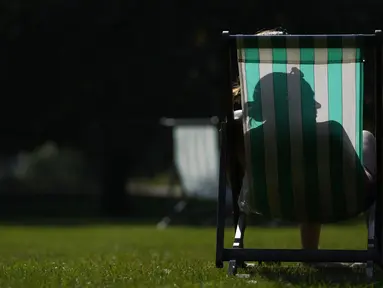 Seorang wanita duduk di kursi di St James' Park London saat suhu diperkirakan mencapai 30 derajat celcius, di London, Selasa, (7/9/2021).  (AP Photo/Alastair Grant)