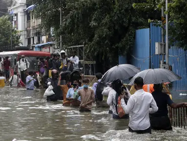 Orang-orang berjalan melewati jalan yang tergenang air setelah hujan lebat di Mumbai, India, Rabu (23/9/2020). Musim hujan di India berlangsung dari Juni hingga September. (AP Photo/Rajanish Kakade)