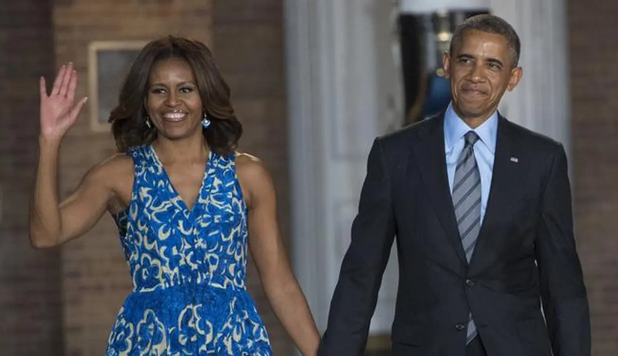 <p>Presiden Amerika Serikat (AS) ke-44, Barack Obama menggandeng tangan sang istri, Michelle Obama, sambil menyapa awak media setibanya pada acara parade di barak marinir AS, Washington, 27 Juni 2014. (AFP PHOTO / SAUL LOEB)</p>