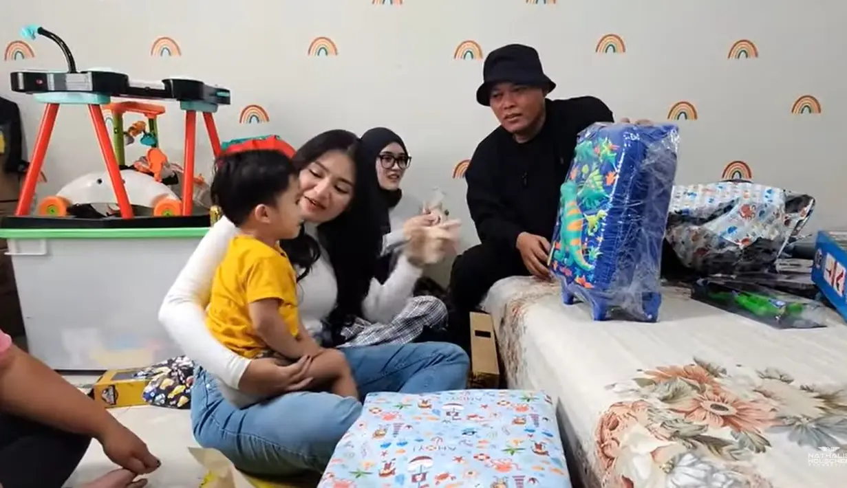 Sule membuka kado satu persatu yang dibawa untuk Adzam. Kado-kado tersebut dari kakak Adzam alias anak-anak Sule dari pernikahan sebelumnya. Setelah membuka kado, lanjut tiup lilin. Sule tampak begitu bahagia merayakan ulang tahun putranya. [Youtube/NATHALIE HOLSCHER]