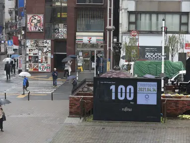 Orang-orang yang memakai masker berjalan di dekat jam hitung mundur untuk Olimpiade dan Paralimpiade Tokyo untuk menandai 100 hari sebelum dimulainya olimpiade musim panas di Tokyo, Rabu (14/4/2021). Olimpiade Tokyo akan dibuka pada 23 Juli 2021. (AP Photo/Koji Sasahara)