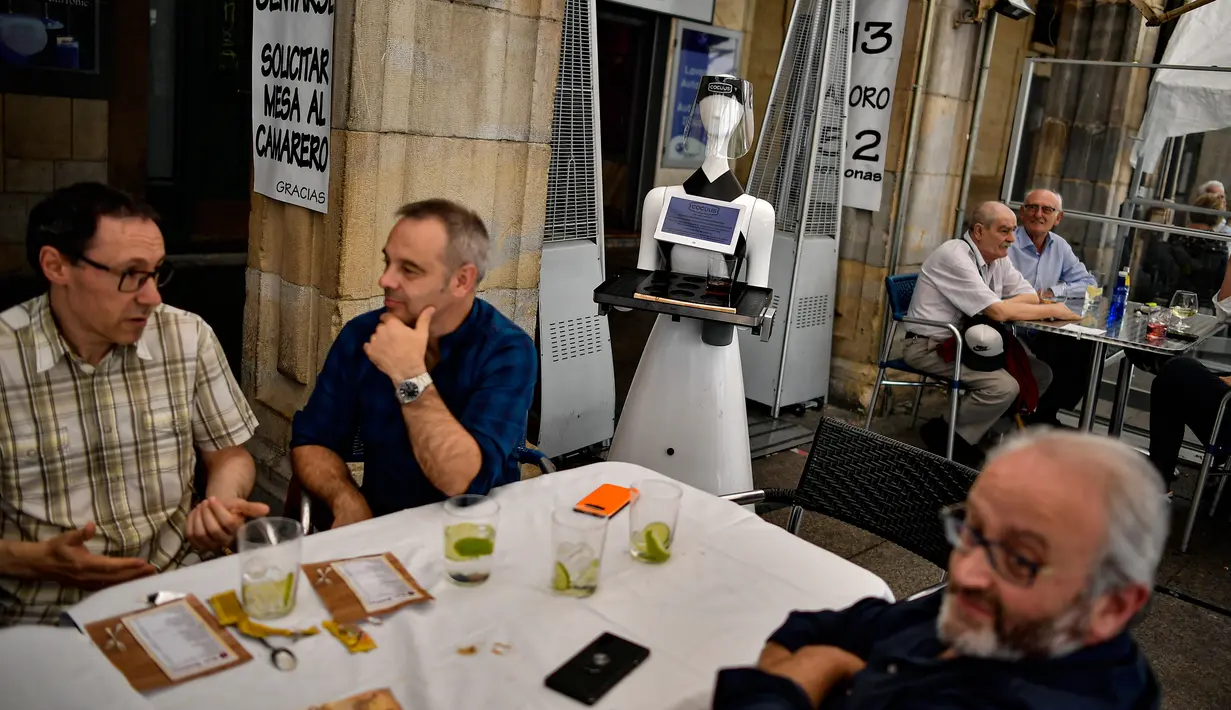Sebuah robot yang dikenal sebagai "Alexia" melayani pengunjung sebuah bar di alun-alun Plaza del Castillo, di Pamplona, Spanyol pada 5 Juni 2020. Robot tersebut digunakan untuk mengurangi penyebaran virus corona Covid-19. (AP Photo/Alvaro Barrientos)