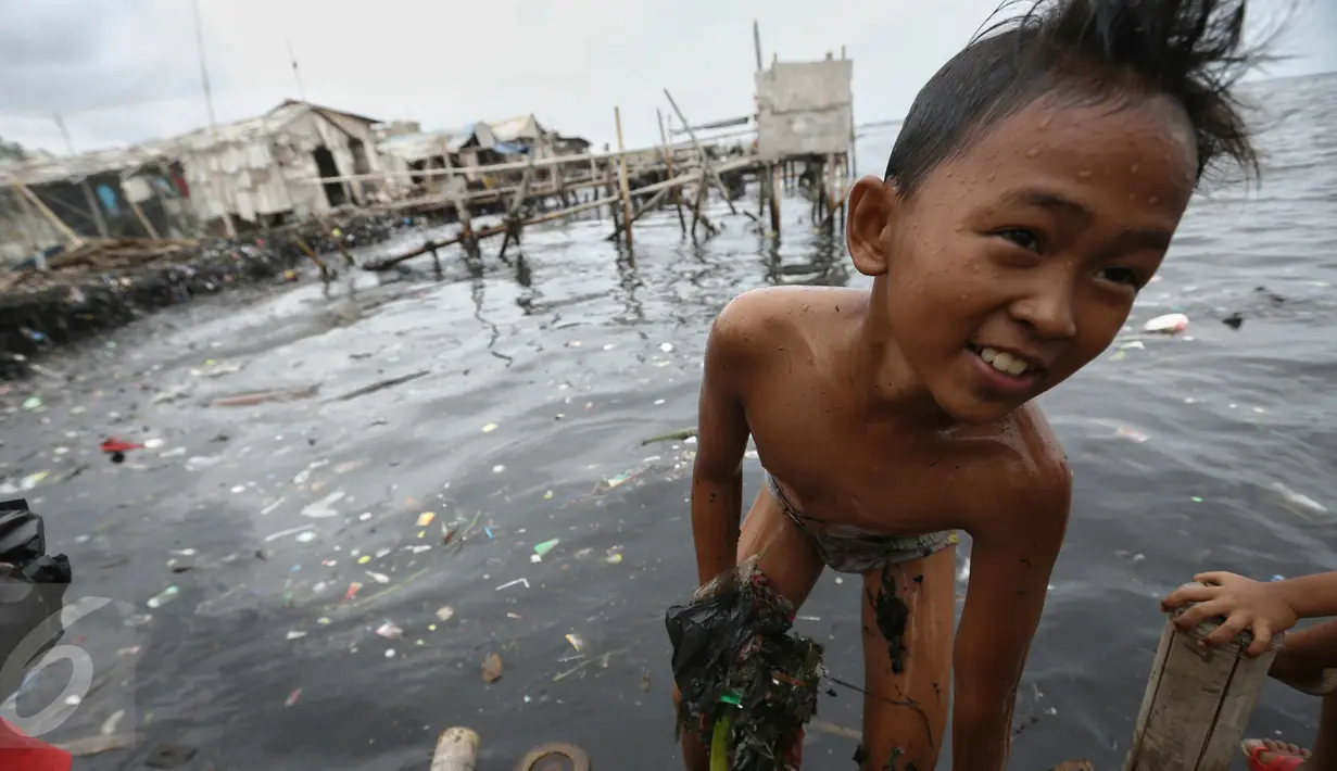 Keceriaan seorang anak saat bermain air di pantai penuh sampah yang terbawa arus di Muara Angke, Jakarta, Rabu (10/2). Genangan sampah yang terbawa arus oleh angin musim barat ini tak menyurutkan anak-anak untuk bermain air. (Liputan6.com/Faizal Fanani)